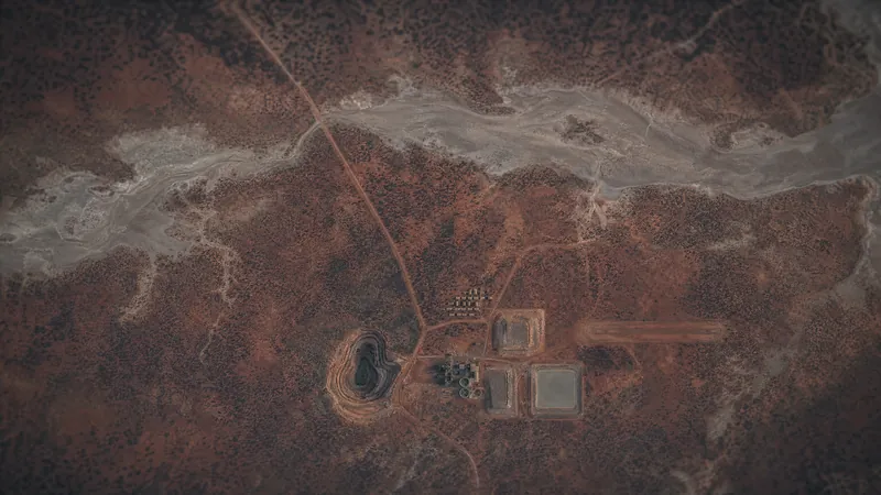 An open pit, process plant, tailings ponds, camp and airstrip seen from directly above on red earth